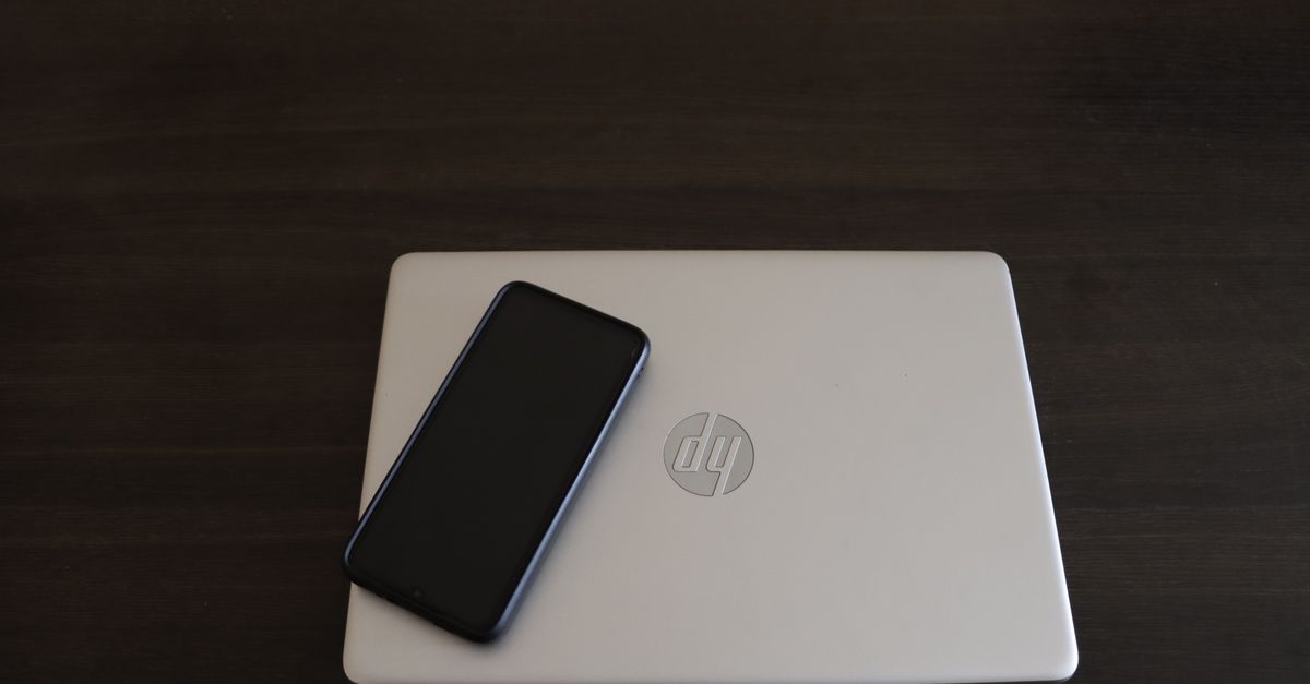 Close-up of a smartphone resting on an HP laptop, symbolizing modern technology integration.