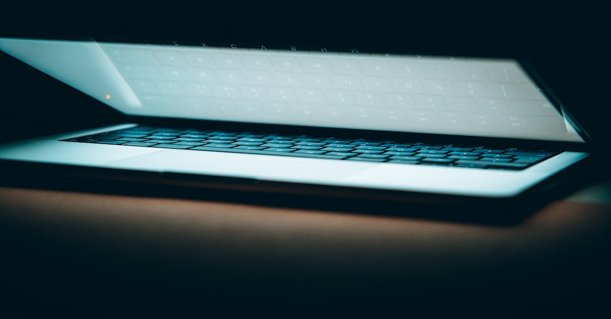 A close-up of a partially open laptop on a wooden surface, displayed in a moody lighting.